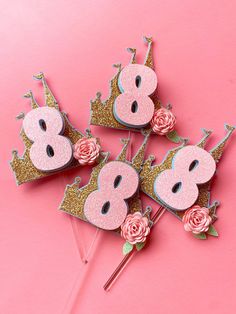 pink and gold birthday cake toppers with number 8 on them, sitting on a pink background