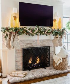 a fireplace decorated for christmas with stockings and lights