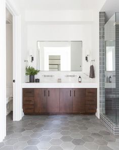 a bathroom with two sinks and a large mirror above the sink, along with a walk in shower