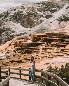 a woman standing on top of a wooden bridge