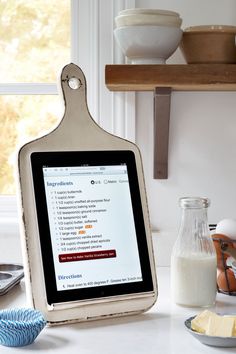 a tablet is sitting on a kitchen counter next to some food and utensils