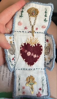 someone is holding up a small piece of cloth with embroidered designs and buttons on it