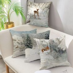 four pillows on a couch with deer in the snow