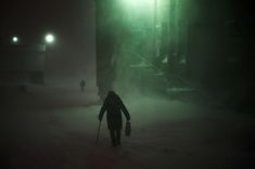 a person walking in the snow at night with a light shining on them and fog