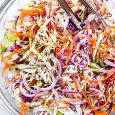 a bowl filled with coleslaw and carrots on top of a white table