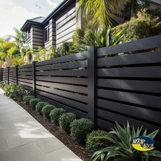 a long black fence is next to some plants