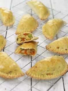 several pastries sitting on top of a wire rack next to each other, with peas and carrots in the middle