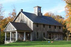 an old barn with a hammock in the front yard and a clock tower