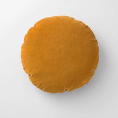 an orange round cushion on a white surface