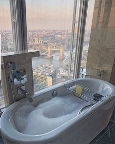 a bathtub in front of a large window with a view of the city below