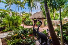 a bird statue in the middle of a tropical garden