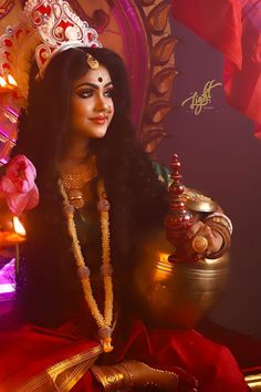 a woman wearing a tiara sitting in front of a gold pot and candle holder