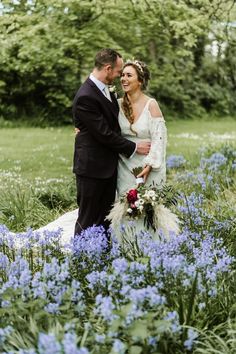 a bride and groom standing in the middle of blue flowers