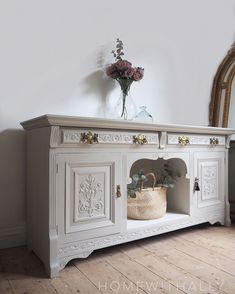 a vase with flowers on top of a white cabinet