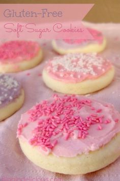 cookies with pink frosting and sprinkles are on a tablecloth that says gluten - free soft sugar cookies