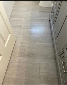 a bathroom with gray cabinets and white tile on the floor is shown in this image