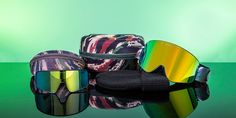 three pairs of ski goggles and sunglasses on a green background