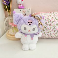 a stuffed animal keychain sitting on top of a table next to a pillow