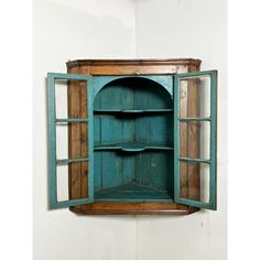 an old wooden cabinet with glass doors on the front and bottom, hanging from a white wall