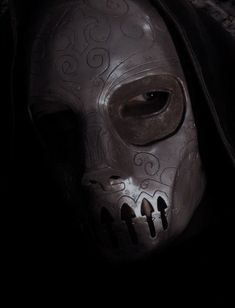 a close up of a person wearing a skull mask in the dark with a hood over their face