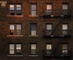 an apartment building with several balconies and two people standing on the balcony at night