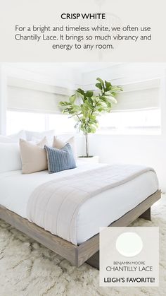 a bed with white sheets and pillows next to a potted plant on top of it