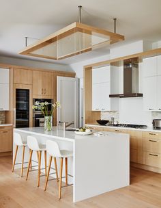 a kitchen with wooden floors and white counter tops next to an island in the middle