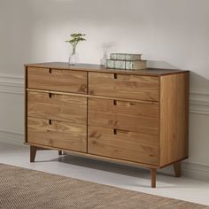 a wooden dresser sitting next to a window in a room with white walls and flooring