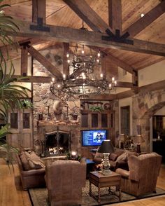 a living room filled with furniture and a chandelier hanging from the ceiling in front of a fireplace