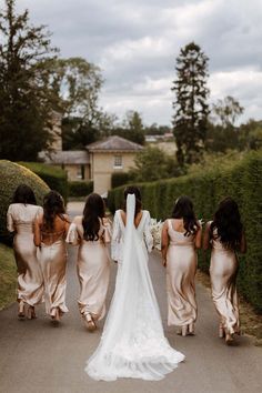 four bridesmaids walking down the road with their backs to each other in dresses