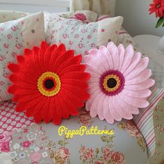 two crocheted flowers sitting on top of pillows