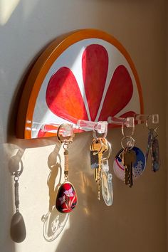 several key chains hanging from the side of a wall next to a circular object with a flower on it