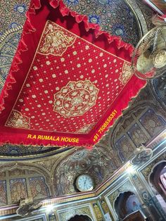 an ornately decorated ceiling with red and gold cloth hanging from it's sides