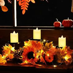 candles are lit in front of autumn leaves and pumpkins