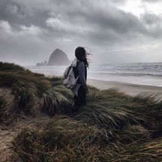 black and white photograph of woman walking on beach with mountains in the backgroud