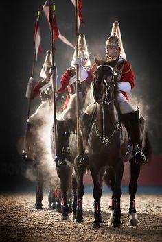 two men dressed as santa claus riding on horses with flags and poles in their hands