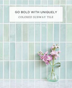 a vase filled with pink flowers sitting on top of a counter next to a tiled wall