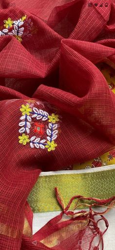 red and yellow sari with floral designs on the border, sitting next to other fabrics