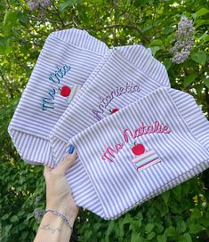 three personalized hand towels are being held up by a woman's hand in front of some trees