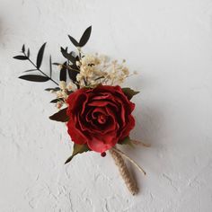 a red rose and some white flowers on a white surface with black leaves in the corner