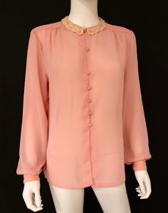 Vintage 1980s feminine long sleeve blouse in peach, featuring a delicate crocheted lace collar, pleating at shoulder tops, and a seven self covered button closure. Soft and with wonderful drape. Designer label removed; fabric label removed - feels like polyester. Retro feminine top, circa 1980s, is in excellent vintage condition. Bottom button missing; not visible when tucked in. Enjoy! *(International Buyers are welcome - however, please email me so I can check the shipping rate for you before Pink Long Sleeve Blouse With Lace Collar, Feminine Long Sleeve Peach Blouse, Feminine Peach Long Sleeve Blouse, Pink Blouse With Lace Collar For Daywear, Vintage Pink Blouse With Peter Pan Collar, Vintage Long Sleeve Pink Blouse, Vintage Pink Long Sleeve Blouse, Vintage Long Sleeve Top With Lace Collar, Pink Long Sleeve Vintage Blouse