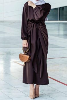 Introducing the Ohlivia Maxi Abaya Dress in rich dark chocolate, crafted with a blend of satin and polyester for a luxurious and comfortable experience. The dress features a detached apron with elasticated sleeves, a tie waist piece, and a flattering pattern that is not oversized. With its versatility, you can wear it front knotted or sideway, adjusting the fit with the apron. To ensure the perfect fit, please refer to the size chart in the next slides, and note that smaller sizes have a shorter Elegant Long Sleeve Brown Abaya, Elegant Long Brown Abaya, Elegant Brown Satin Maxi Dress, Formal Brown Satin Maxi Dress, Brown Satin Maxi Dress For Evening, Evening Satin Maxi-length Abaya, Modest Long Brown Maxi Dress, Brown Satin Maxi Length Dress, Evening Satin Maxi Abaya