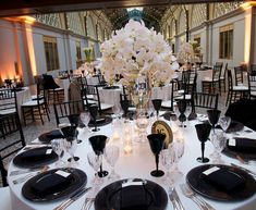 the table is set with black and white plates, silverware, and centerpieces