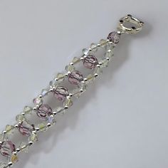 a close up of a bracelet made out of glass beads and silver metal chains on a white surface