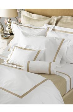 a bed with white and beige sheets and pillows