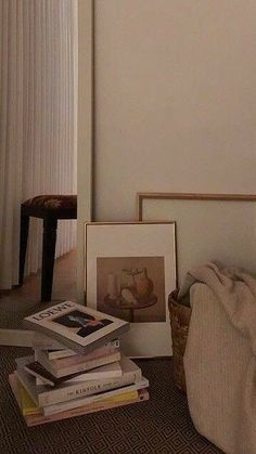 a pile of books sitting on top of a floor next to a basket filled with pictures