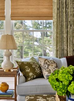 a living room filled with furniture next to a window covered in green and white curtains