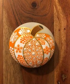 an orange and white painted pumpkin sitting on top of a wooden table next to a wall