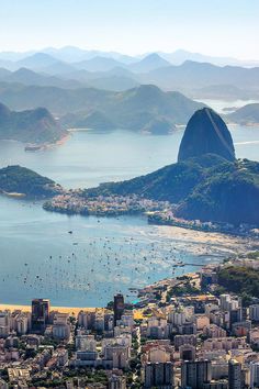 an aerial view of a city with mountains in the background and boats on the water