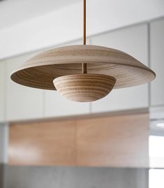 a wooden light fixture hanging from a ceiling in a room with white walls and cabinets